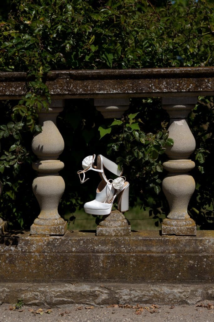 The bride’s heels rest on a stone balustrade framed by ivy, photographed as an elegant detail from a Waterford estate wedding.