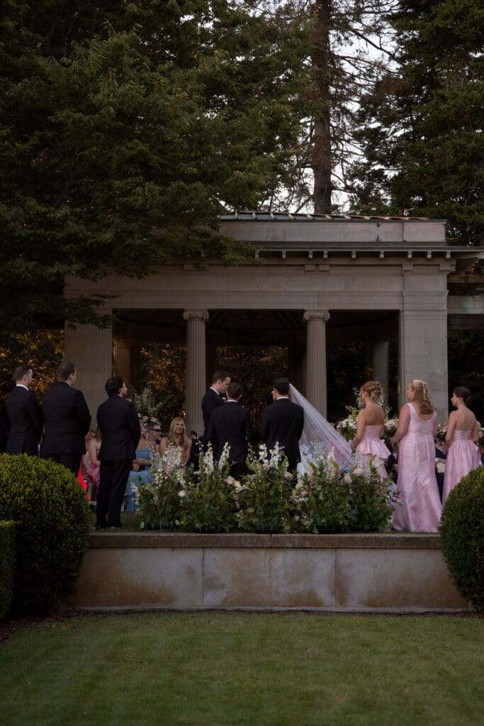 Guests and the wedding party gather near the pergola as the ceremony begins on the grounds, photographed by a wedding photographer CT for estate weddings.