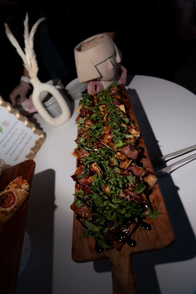 A long wooden board topped with greens and grilled bites is styled as an elevated reception detail at a romantic wedding venue in Connecticut.