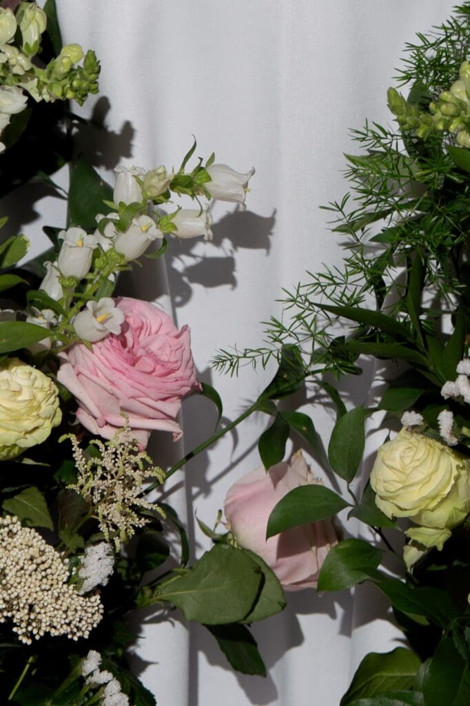 Soft pink and ivory flowers climb a white backdrop in a close editorial detail from a garden wedding venue in Connecticut.
