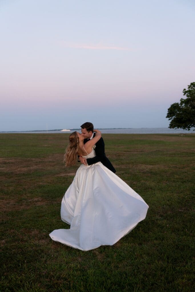 At dusk, the bride and groom embrace in an open field with her gown billowing around them at one of the most scenic best wedding venues in Connecticut.