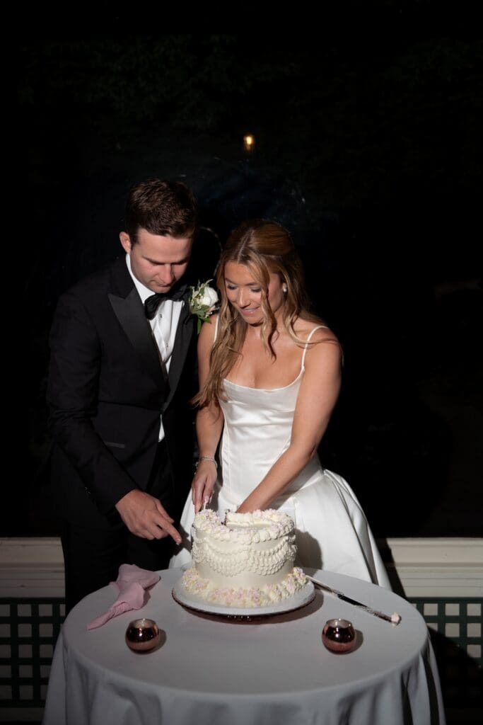 The newlyweds cut their cake by candlelight under the night sky in a quiet, intimate reception moment from one of the best Connecticut wedding venues.
