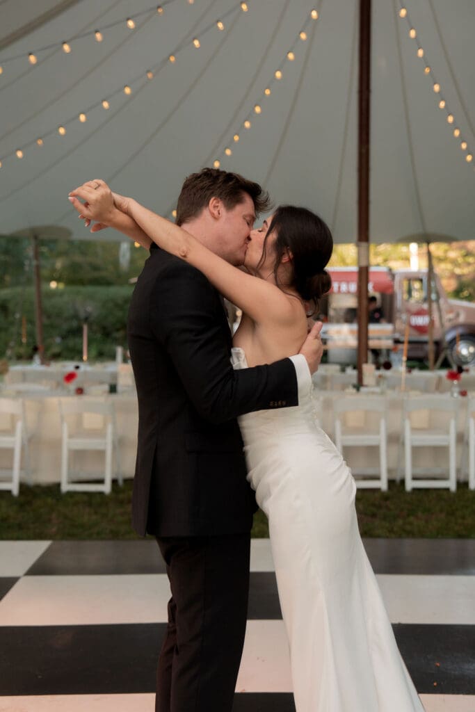 The couple shares their first dance beneath a sailcloth tent and string lights during a reception at a classic Connecticut wedding venue.