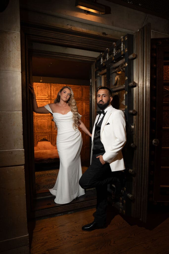 The couple poses in the open doorway beneath carved wood and stone, creating a dramatic estate portrait at one of the best wedding venues in Connecticut.