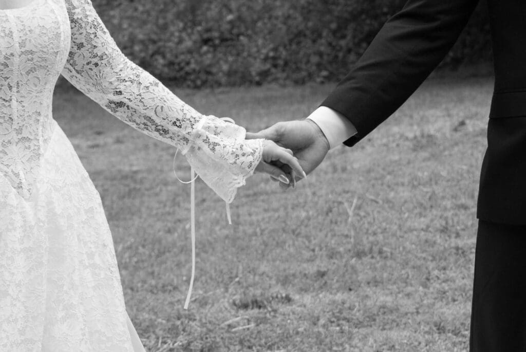 In black and white, the couple’s hands meet in a quiet close-up that feels timeless and intimate at a Wadsworth Mansion wedding venue.
