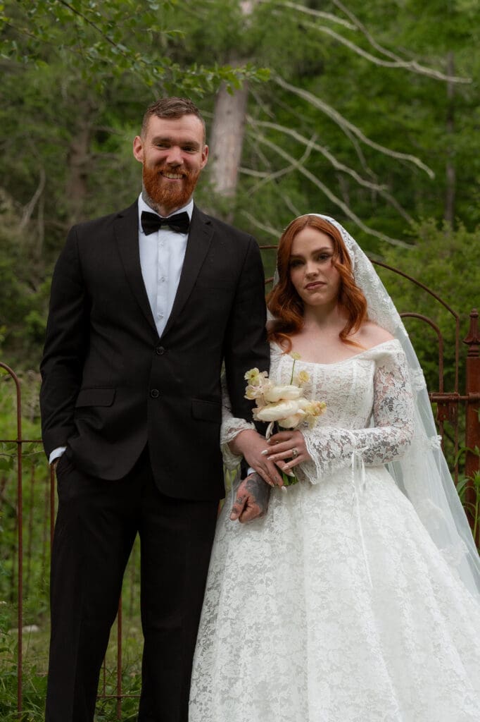 Bride and groom stand together in a formal portrait against the greenery, framed as timeless imagery by a Connecticut wedding photographer.