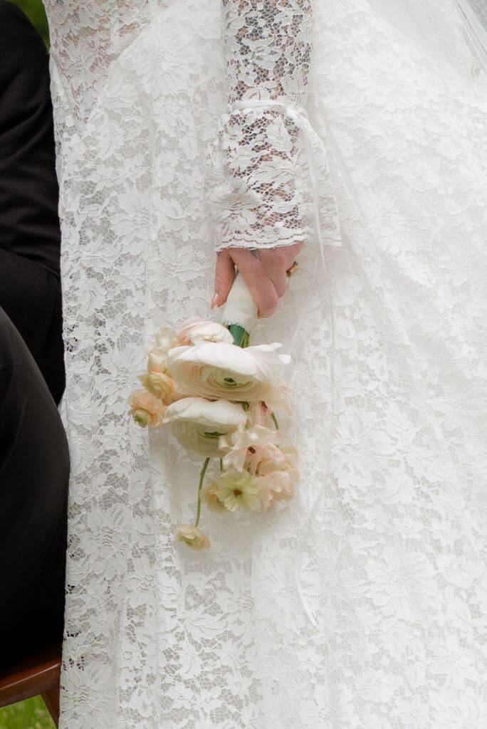 A close view of the bride’s lace gown and bouquet highlights the texture and softness of the look, photographed by a CT wedding photographer.