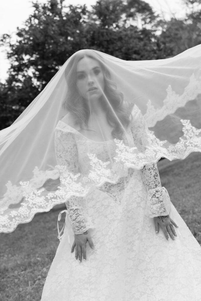 Seen through her lace-edged veil, the bride is framed in a black-and-white portrait that feels soft and timeless, photographed by Wedding Photographers CT.