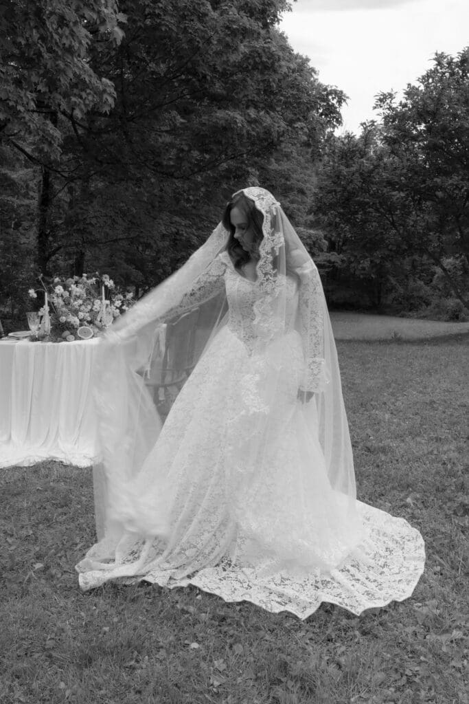 The bride lifts her veil across the lawn in a quiet, cinematic portrait from a romantic Connecticut wedding photographer perspective.